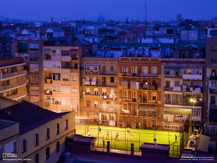 Barcelona cityscape at dusk with people playing soccer