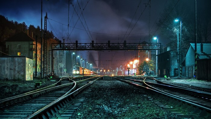 Train station at night with multiple tracks and overhead wires