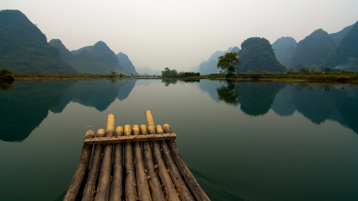 Bamboo raft on a misty river with karst mountains