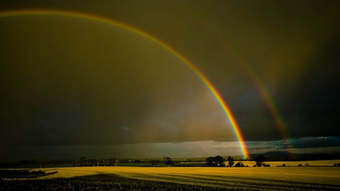 Double rainbow over a field at sunset