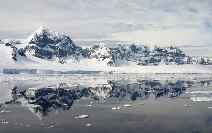 Snow-covered mountains reflected in icy water
