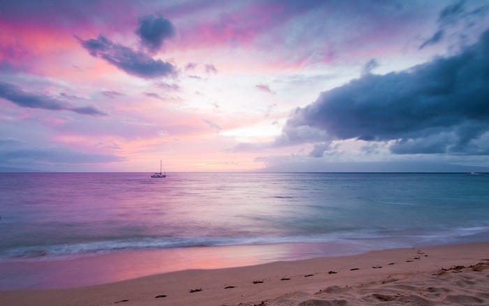 Sailboat on the ocean at sunset with colorful clouds