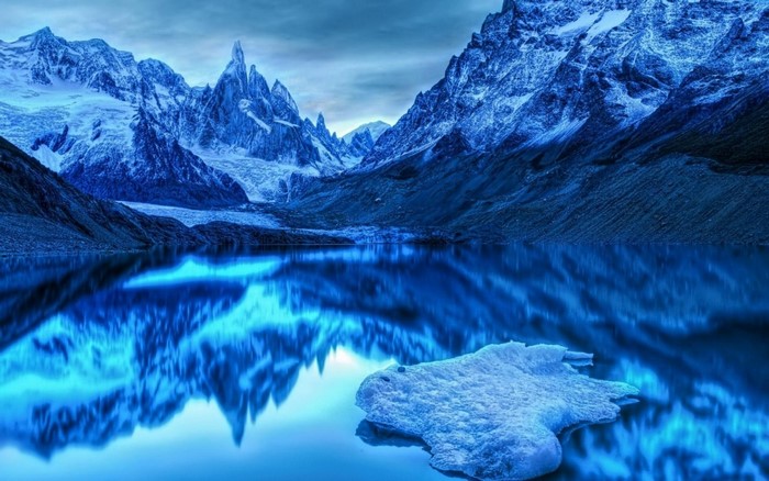 Snow-capped mountains reflected in a glacial lake with ice floe