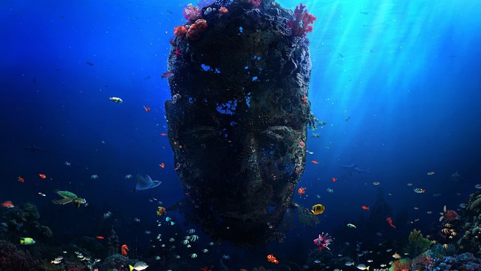 Underwater face sculpture with coral and fish