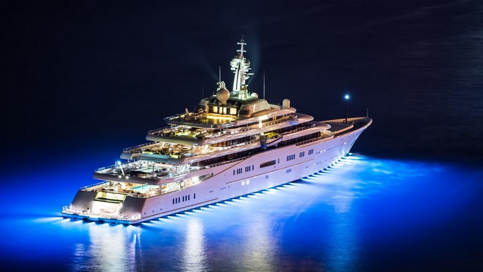 Luxury yacht illuminated at night with blue underwater lights
