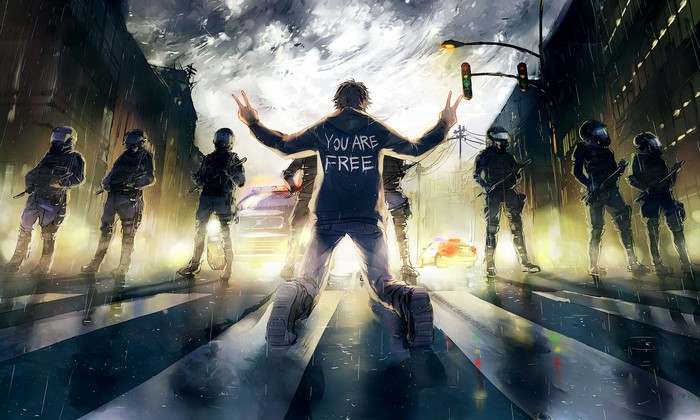 Man with 'You Are Free' on hoodie facing riot police
