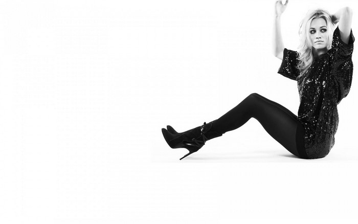 Yvonne Strahovski sitting in black sequined top and boots