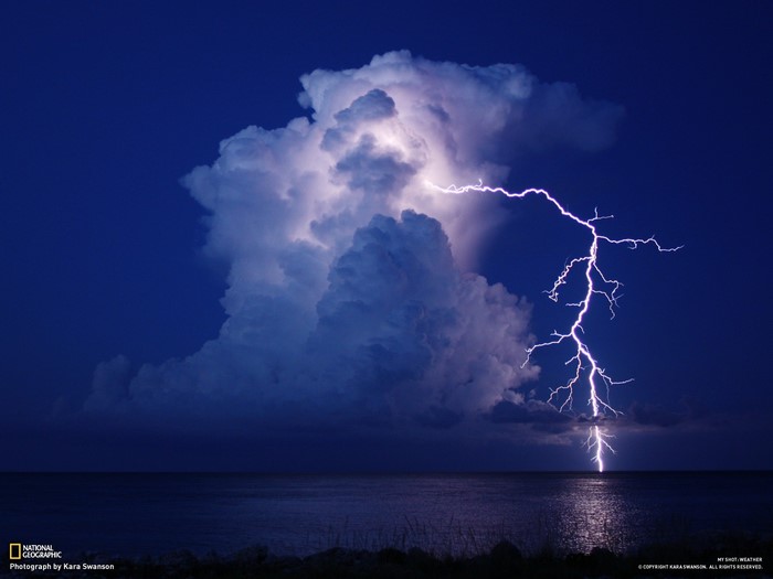 Lightning strikes the ocean during a thunderstorm over the sea