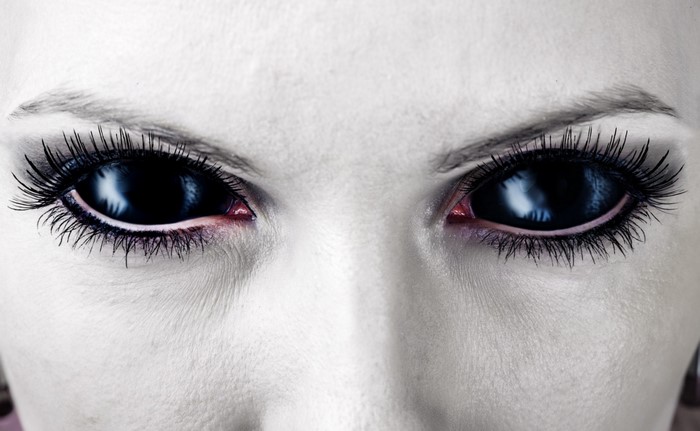 Close up of a person's face with black eyes