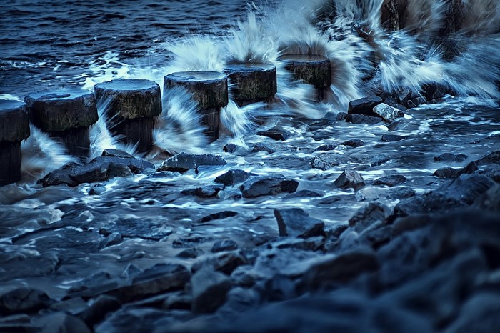 Waves crashing on wooden posts and rocks