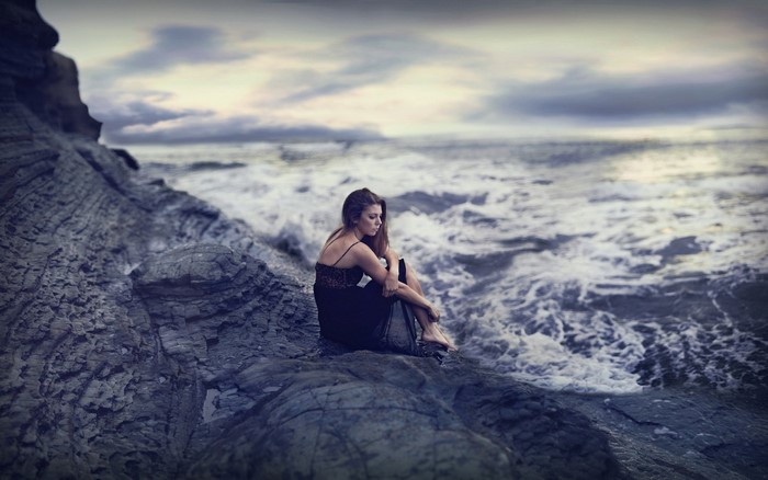 Woman sitting on rocks by the ocean