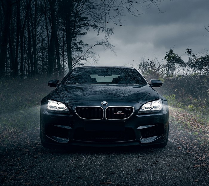 Black BMW M6 parked on a dirt road in a forest