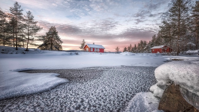 Red cabins in a snowy landscape at sunset