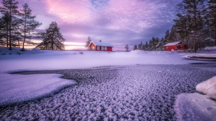 Red cabins in a snowy landscape at sunset