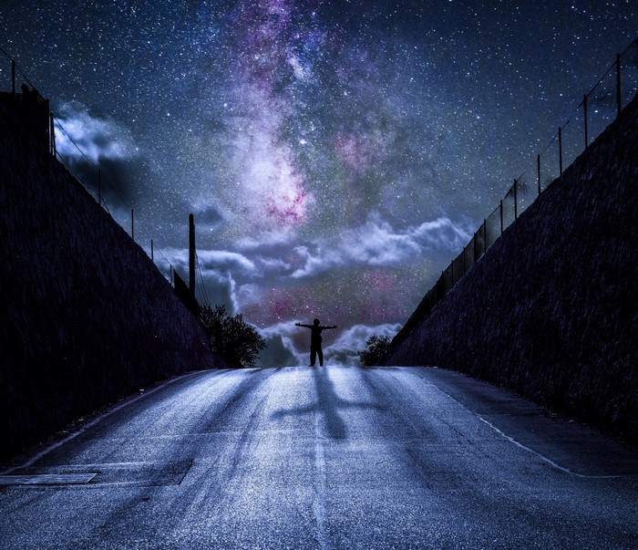 Silhouette on a road under the Milky Way