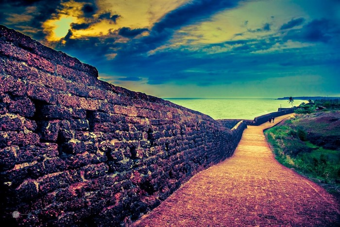 Stone wall path along the sea under dramatic sky