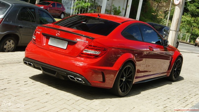 Red Mercedes Benz C63 AMG Coupe parked on brick pavement