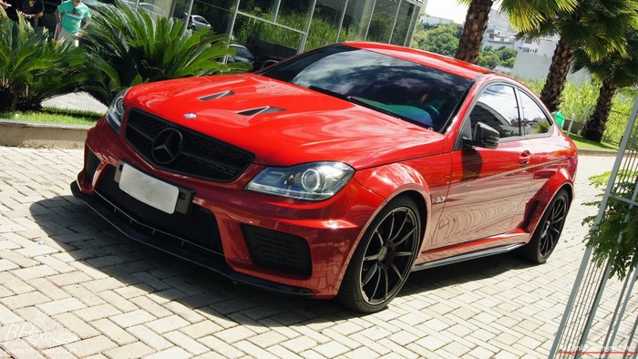 Red Mercedes Benz C63 AMG Coupe parked on brick pavement
