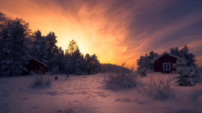 Snowy landscape with red cabins at sunset