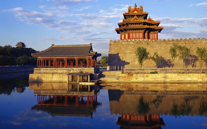 Traditional Chinese architecture reflected in water at dusk