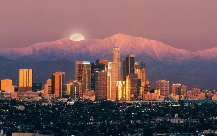 Cityscape with mountains and moon at sunset