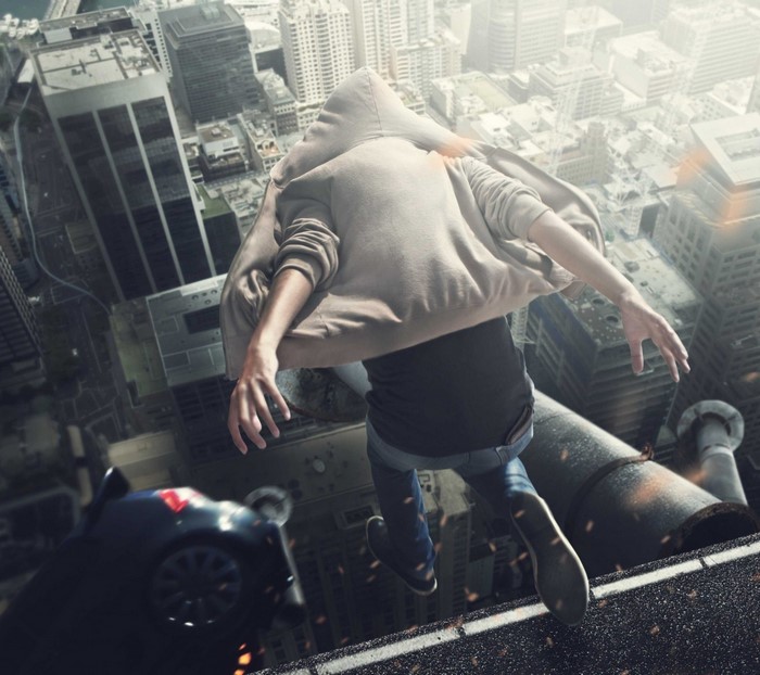 Man in hoodie jumping off a skyscraper