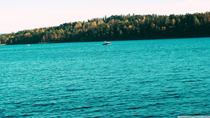 Boat on a turquoise lake with a forest background