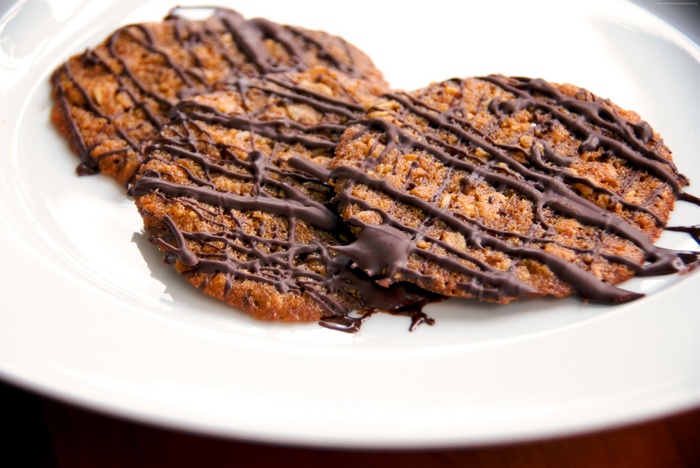 Chocolate drizzled oatmeal cookies on a white plate