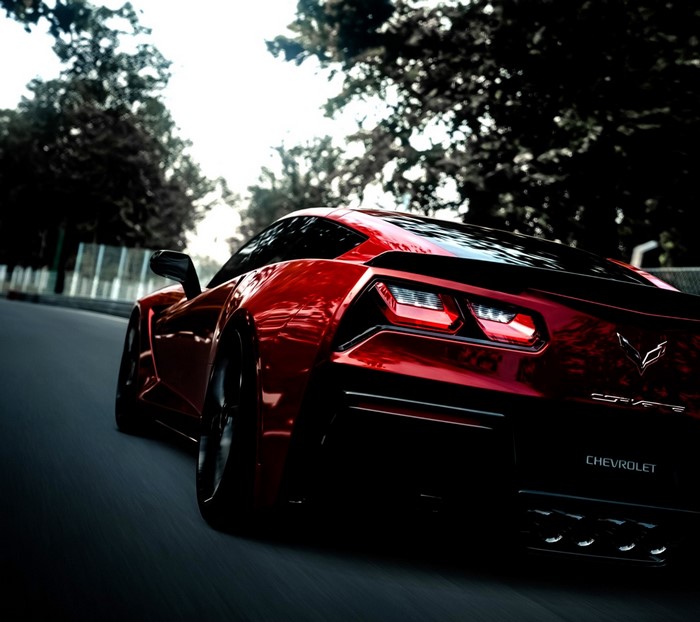 Red Chevrolet Corvette driving on a road