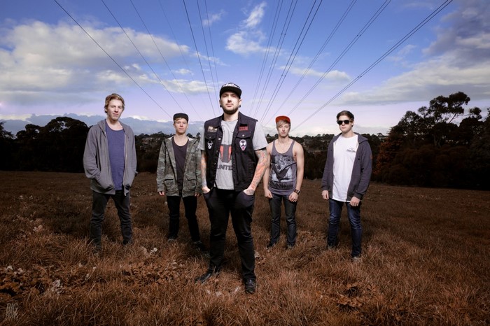 Five men standing in a field with power lines overhead