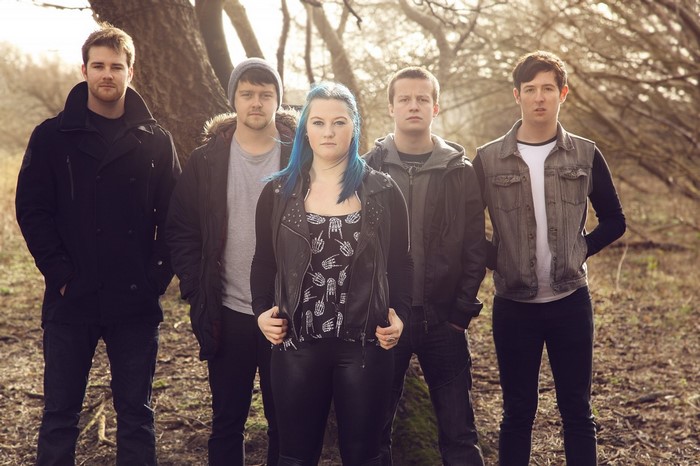 A band of five musicians posing outdoors