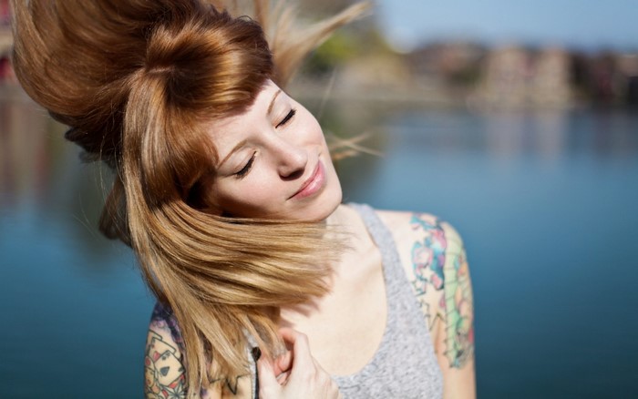 Woman with red hair and tattoos by the water