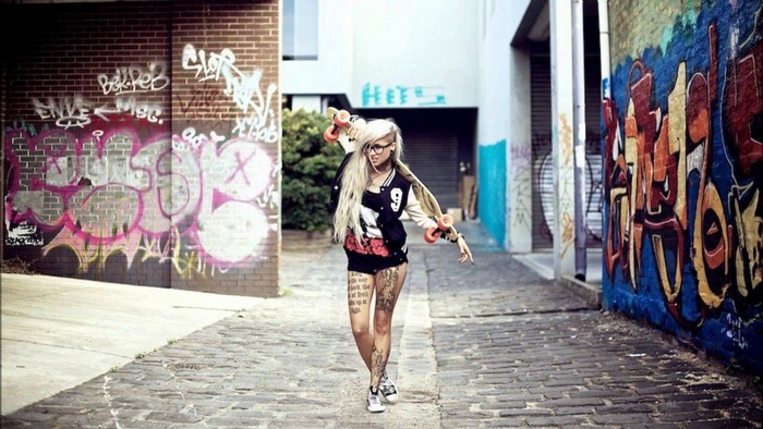 Woman with longboard in graffiti alley