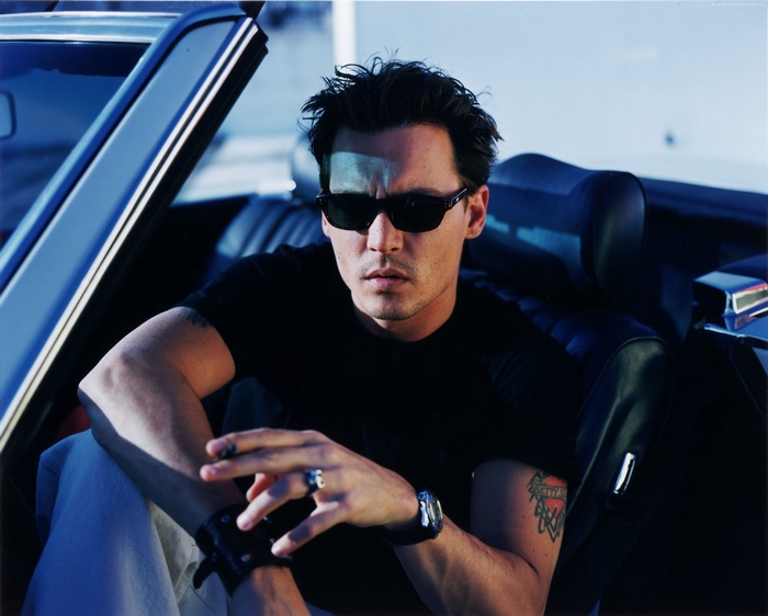 Johnny Depp in a car wearing sunglasses and holding a cigarette