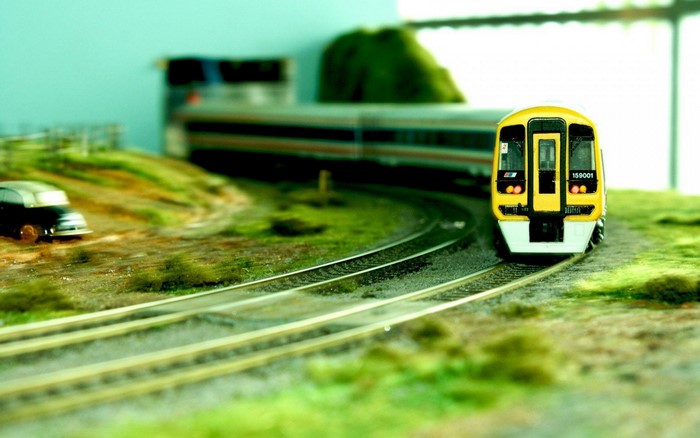 Model train on a miniature railway track with a car