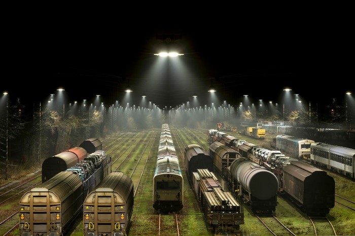 Nighttime train yard with multiple trains and lights