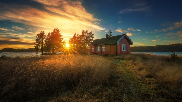 Red cabin by a lake at sunset