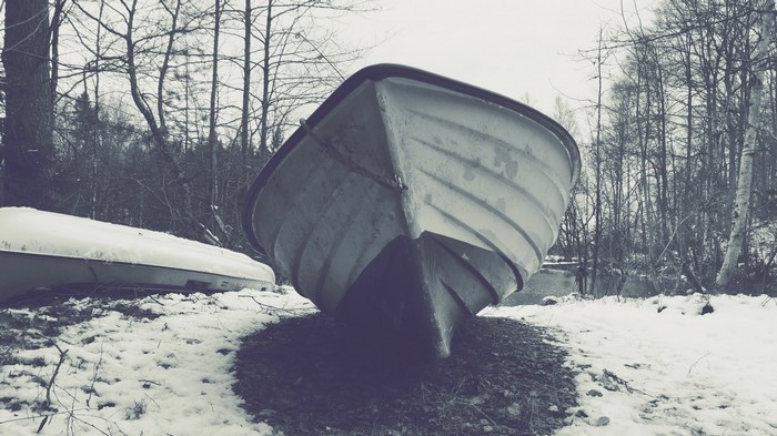 Two boats on a snowy shore with bare trees