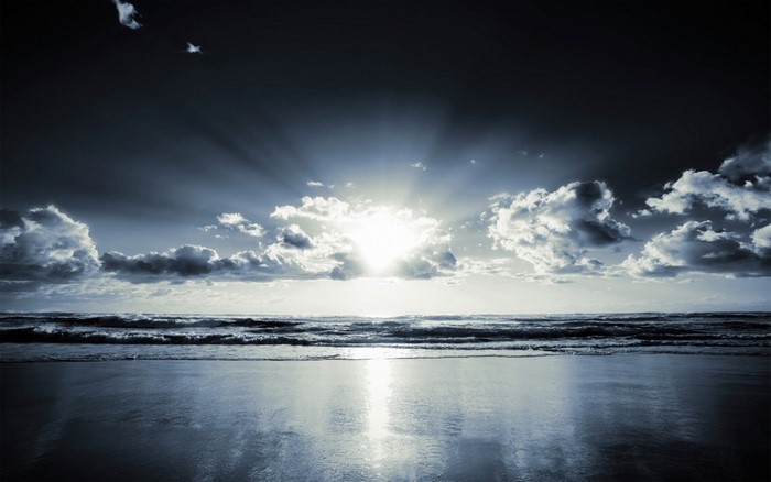 Sunlight breaking through clouds over the ocean at dawn