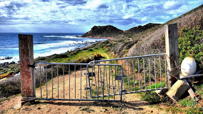 Metal gate on a coastal path overlooking the sea