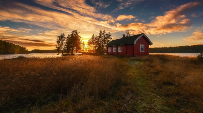Red cabin by a lake at sunset