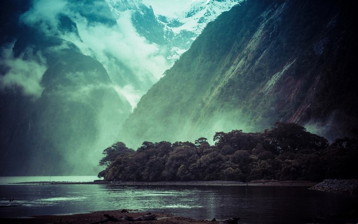 Misty mountains over a dark lake and forest