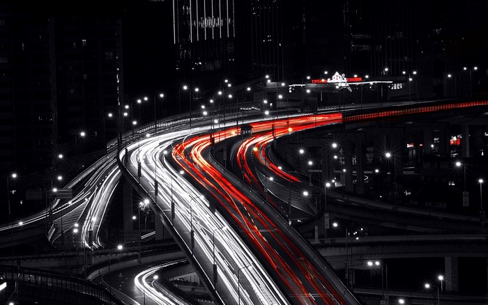 Cityscape at night with light trails on highways