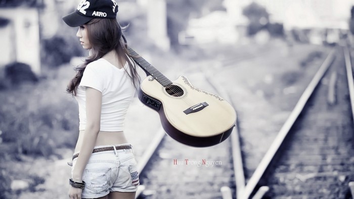 Woman with guitar on railway tracks