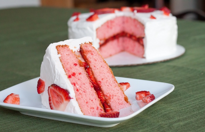 Strawberry cake with white frosting and fresh strawberries
