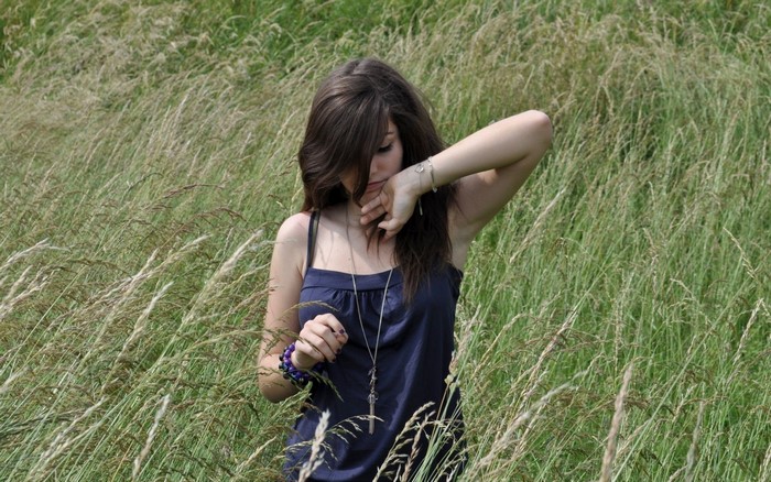 Young woman with long brown hair in a field of tall grass
