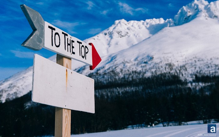 Sign pointing to the top of a snowy mountain