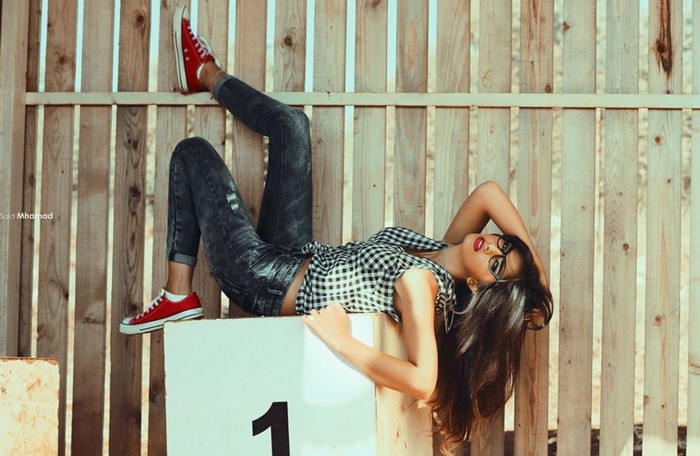 Woman in jeans and checkered shirt posing on blocks
