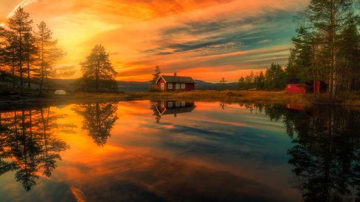 Red cabin reflected in a lake at sunset