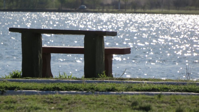 Picnic table and bench by a shimmering lake